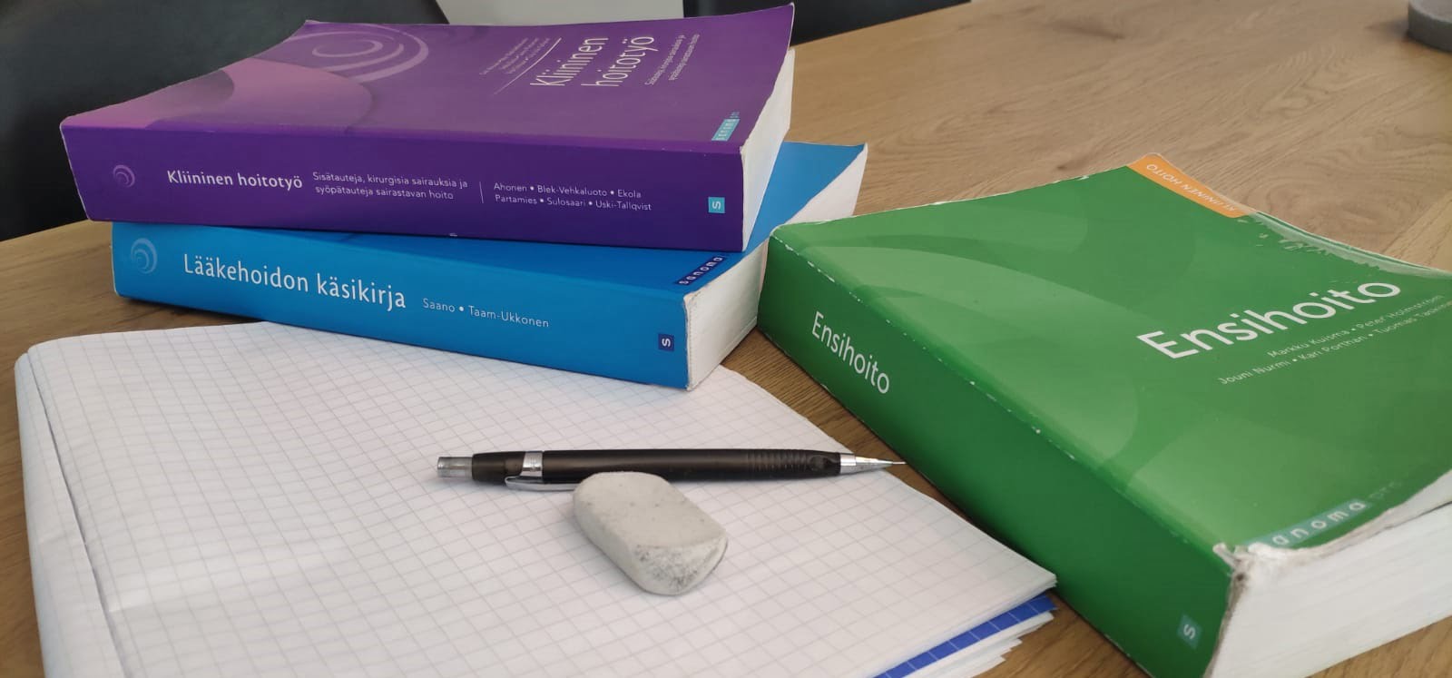 Ensihoidon oppikirjoja ja muistiinpanovälineet.