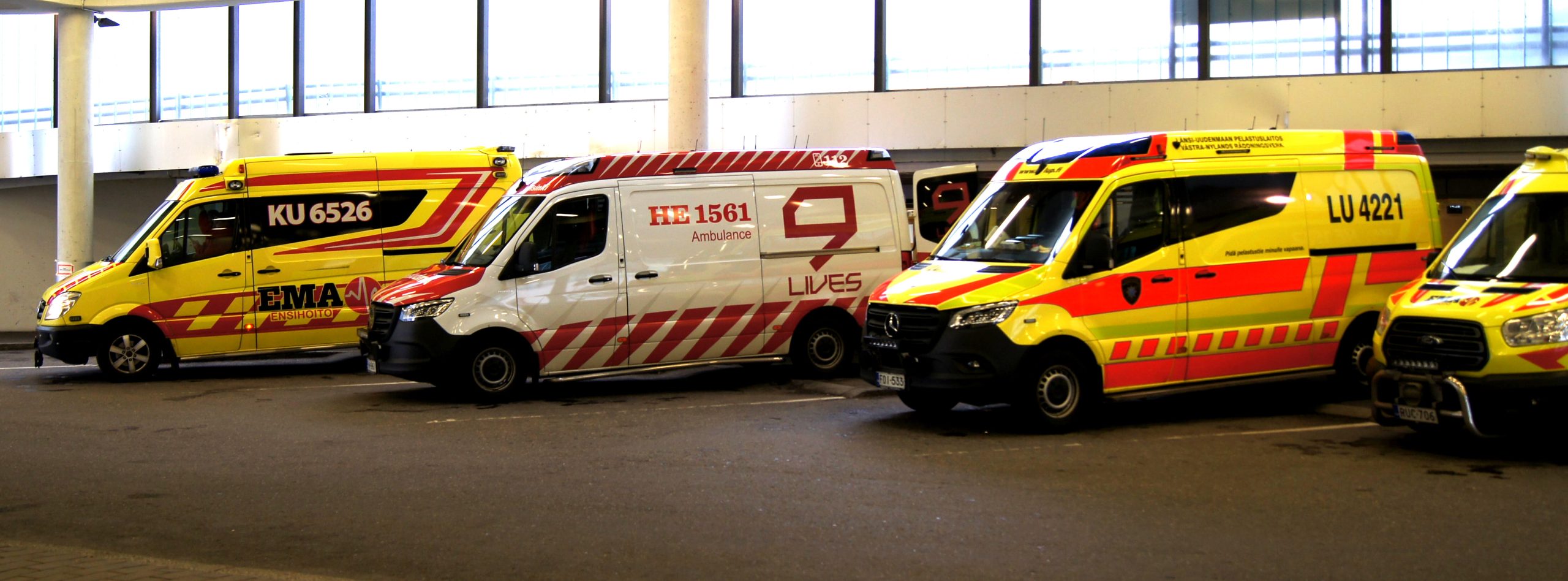 Neljä ambulanssia sairaalan ovien edessä parkissa.