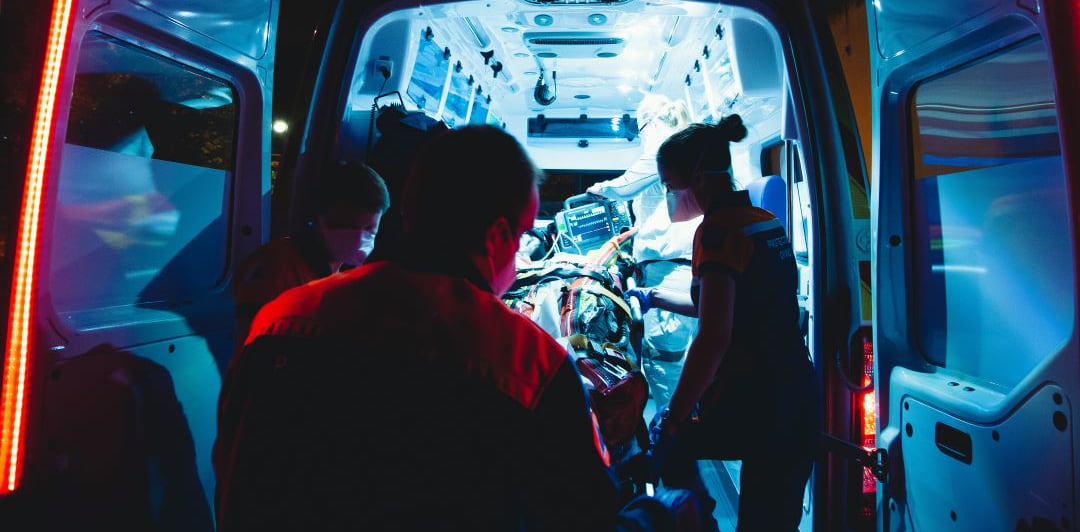 Ensihoitajat nostamassa potilasta paareilla ambulanssiin.